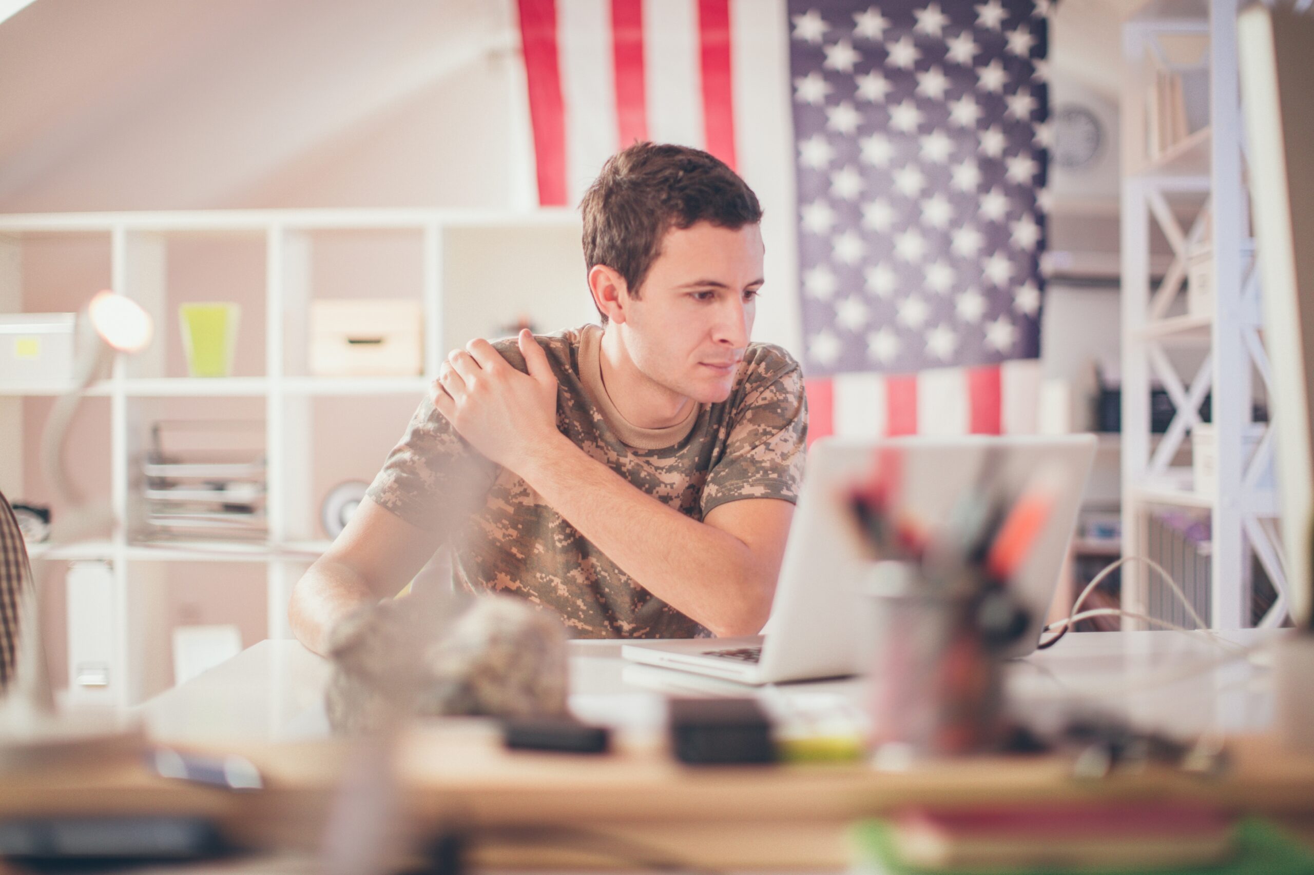 A man in military uniform seated at a desk, focused on his laptop, exemplifying professionalism and dedication.