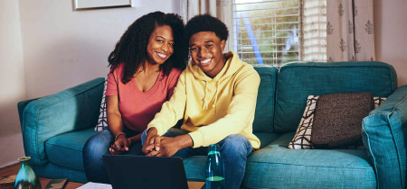 Mom and son sit together on a couch, focused on a laptop, sharing a moment of connection and collaboration.