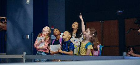 A group of children gathered around a screen, attentively watching and engaging with the content displayed.