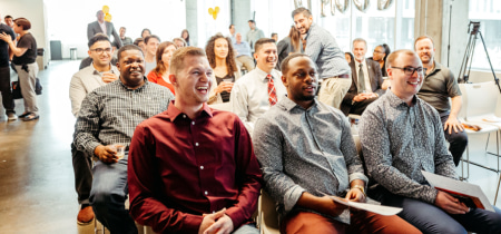 A group of individuals seated in a room, with one man prominently smiling, creating a warm and inviting atmosphere.