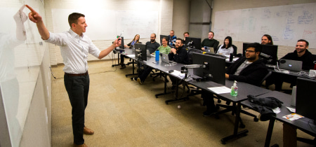 A man presents to an audience, engaging them with his speech and visual aids in a professional setting.