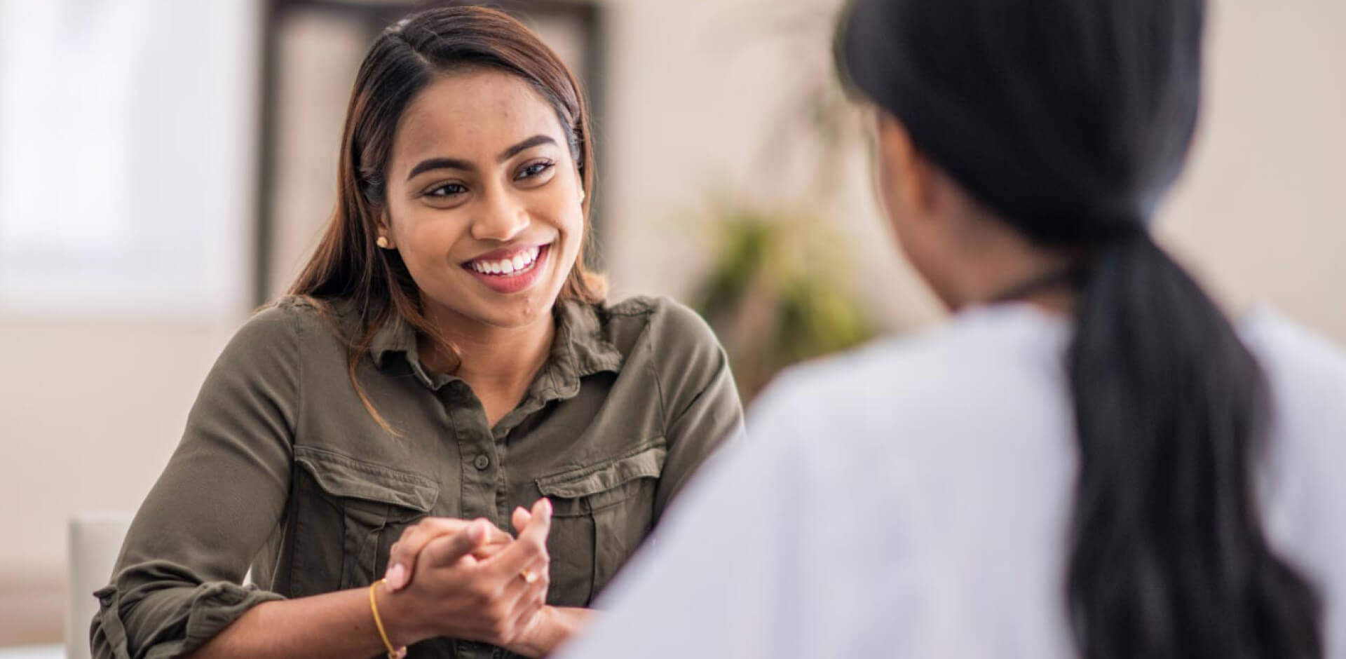 A woman engages in conversation with another woman during a professional meeting setting.